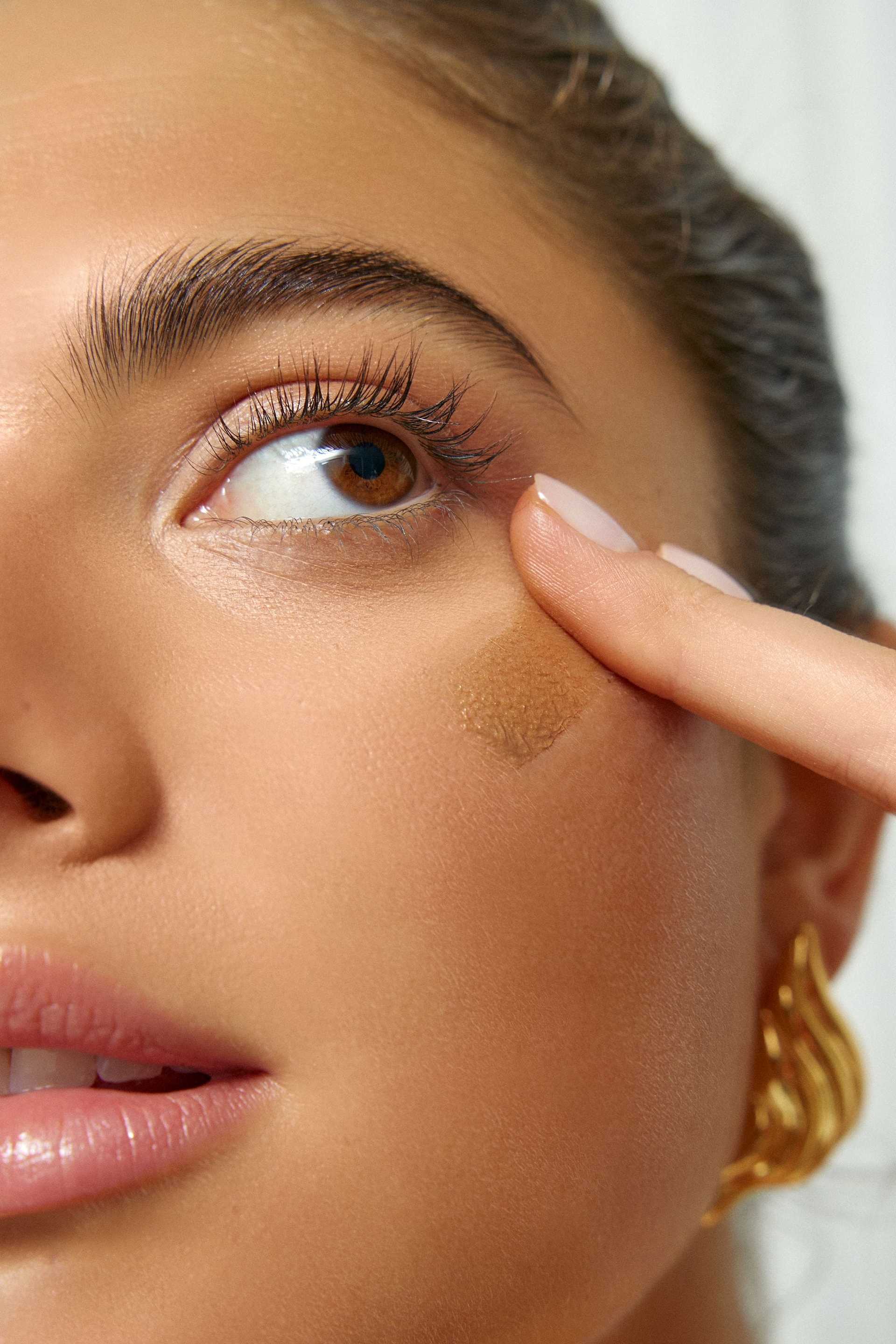 Woman applying makeup under eye.