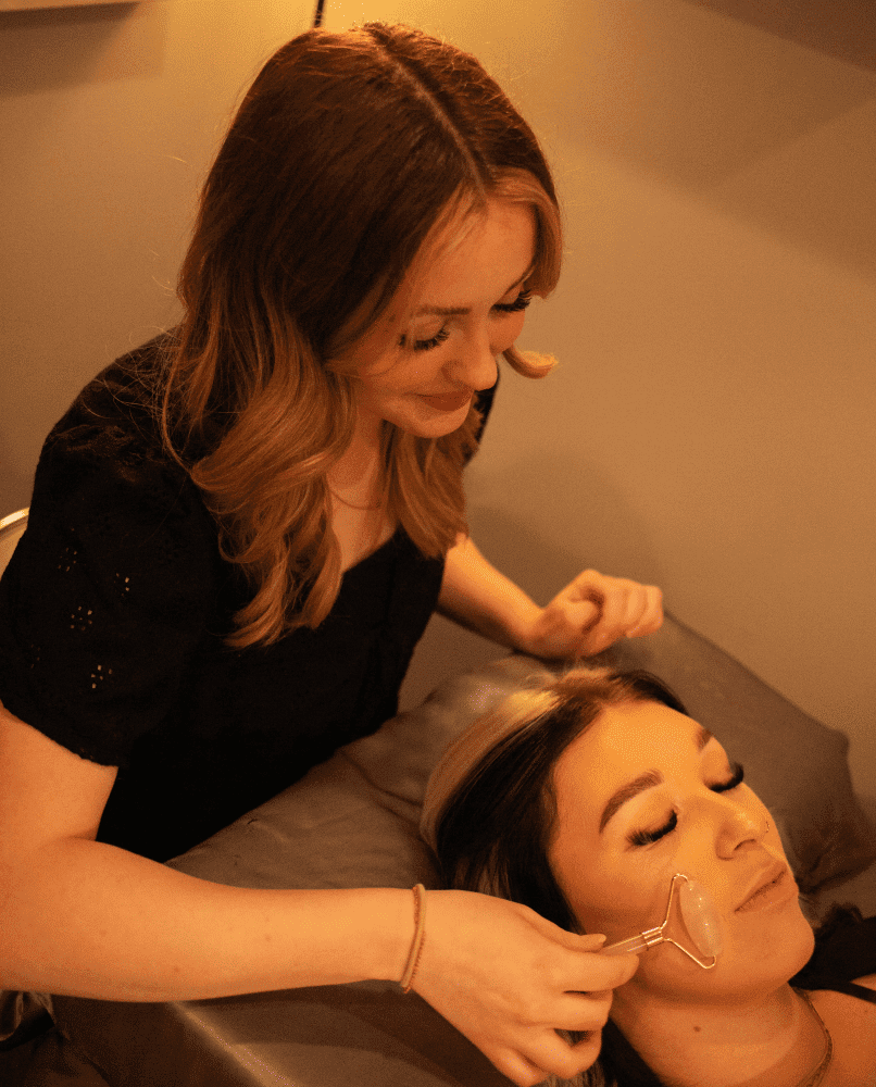 Woman receiving relaxing facial massage with a jade roller in a spa setting.