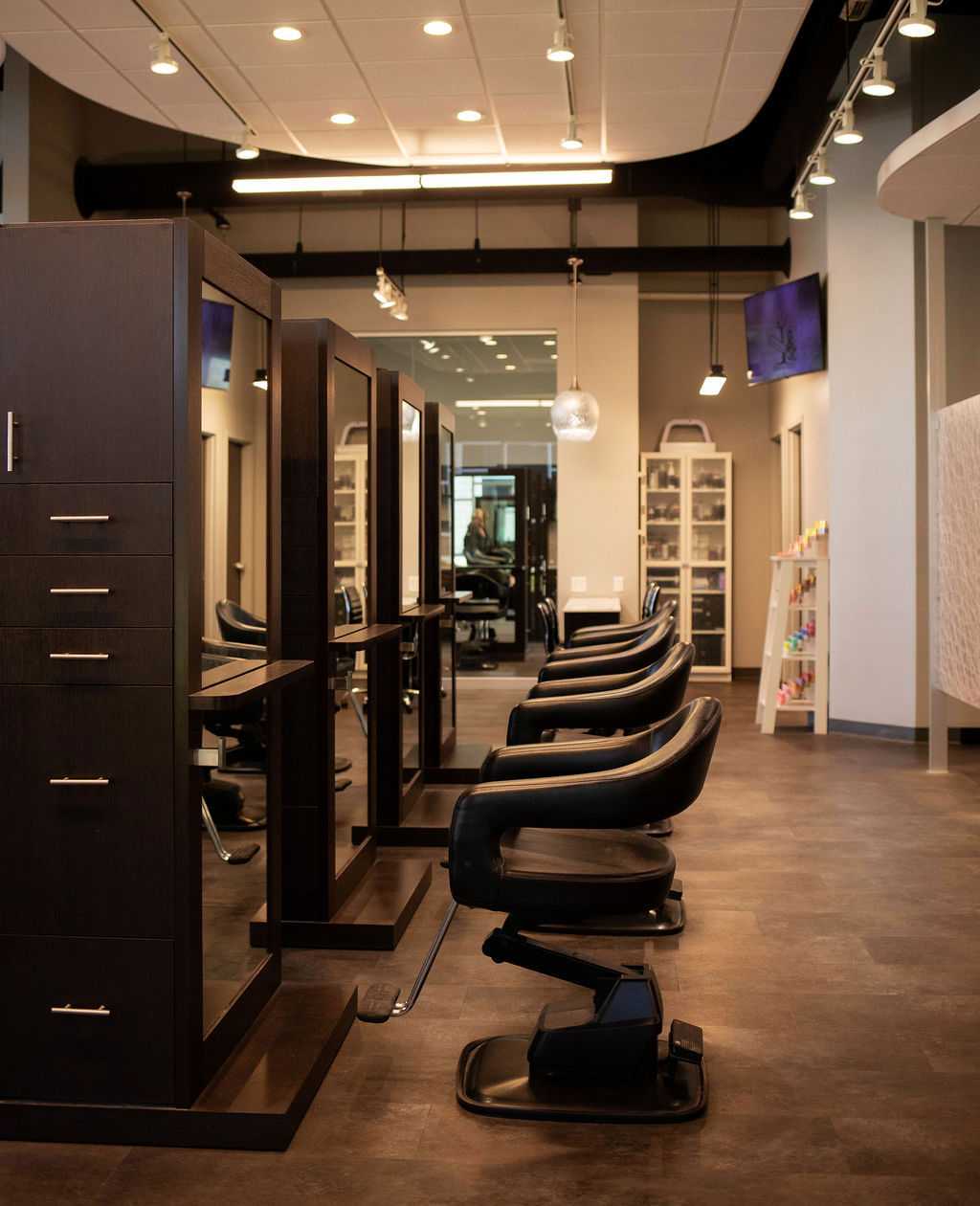 Upscale hair salon interior with modern black chairs and sleek wooden styling stations.